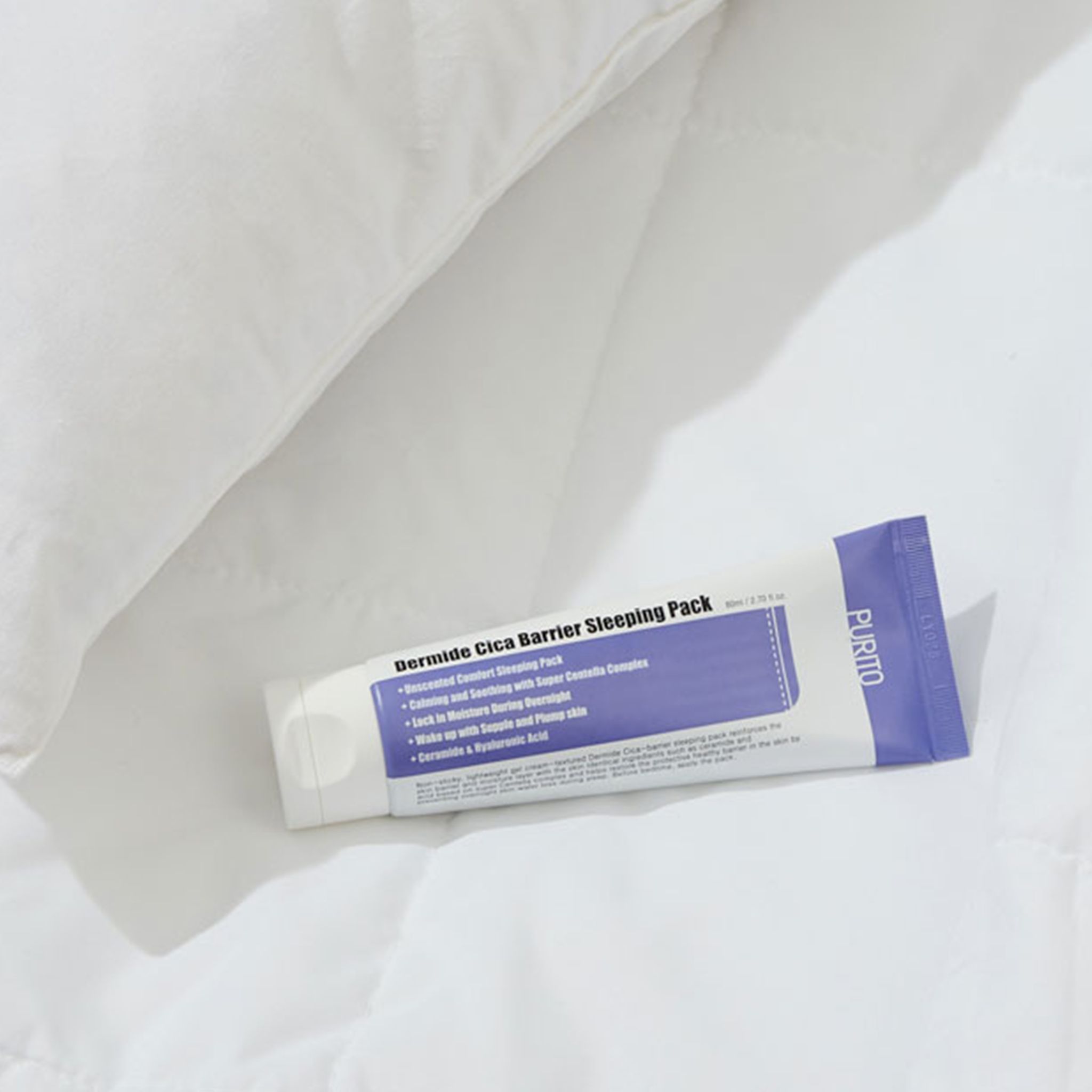 Product op wit beddengoed. Tube met productnaam en ingrediënten. Merk PURITO. Tekst: Dermide Cica Barrier Sleeping Pack.