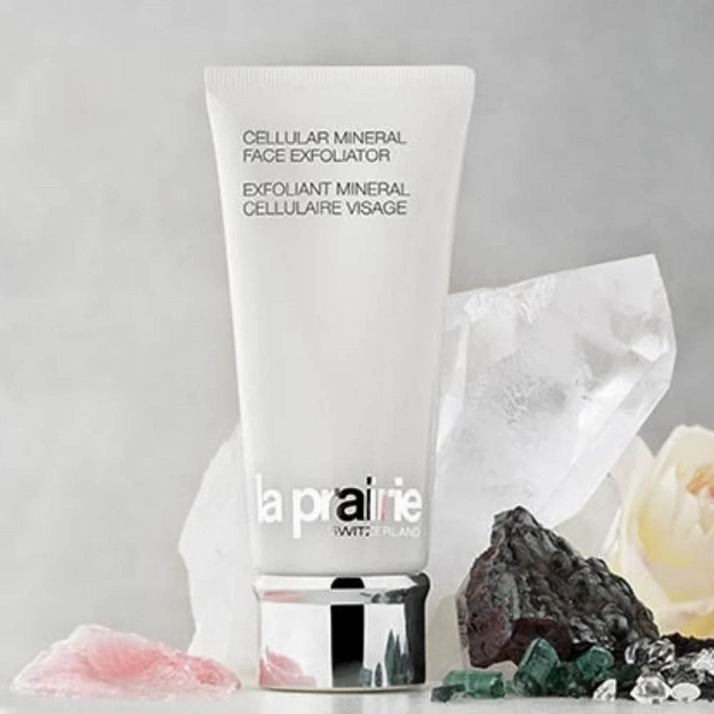 Witte tube met producttekst en logo. Omringd door stenen en bloemen. Merk: La Prairie.