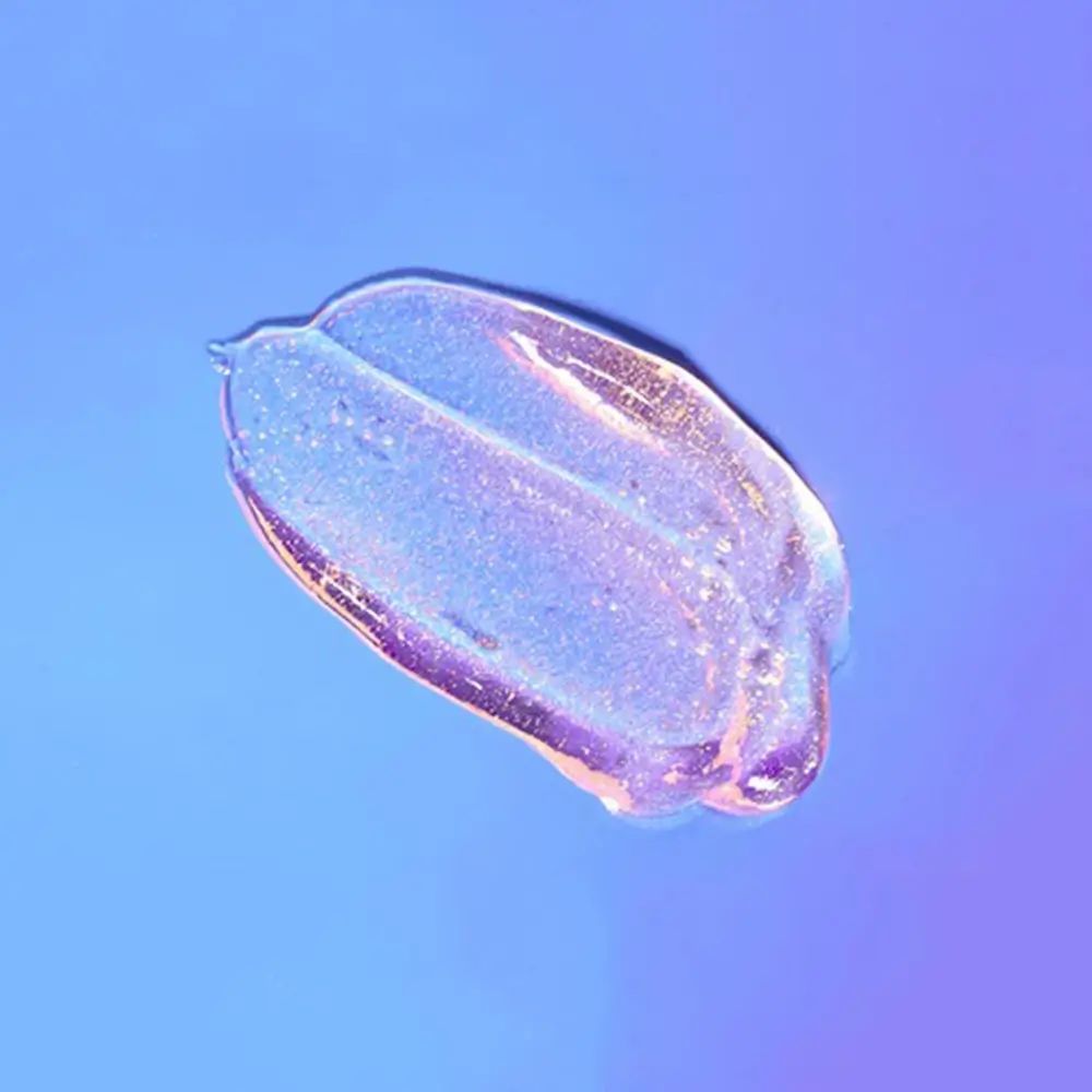 Substance gélifiée scintillante sur fond bleu. Dégradé de clair à foncé. Particules scintillantes visibles.