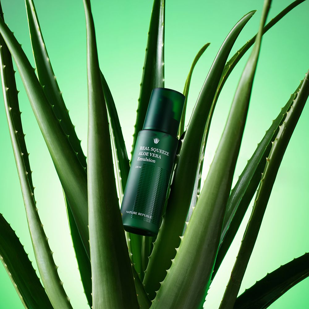 Flacon vert devant des feuilles d'aloe vera. Inscription: REAL SQUEEZE ALOE VERA Emulsion. Marque NATURE REPUBLIC.