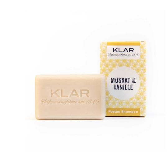 Beige zeep en verpakking. Zeep met Klar-logo. Verpakking: Klar, Muskat & Vanille, vaste shampoo.