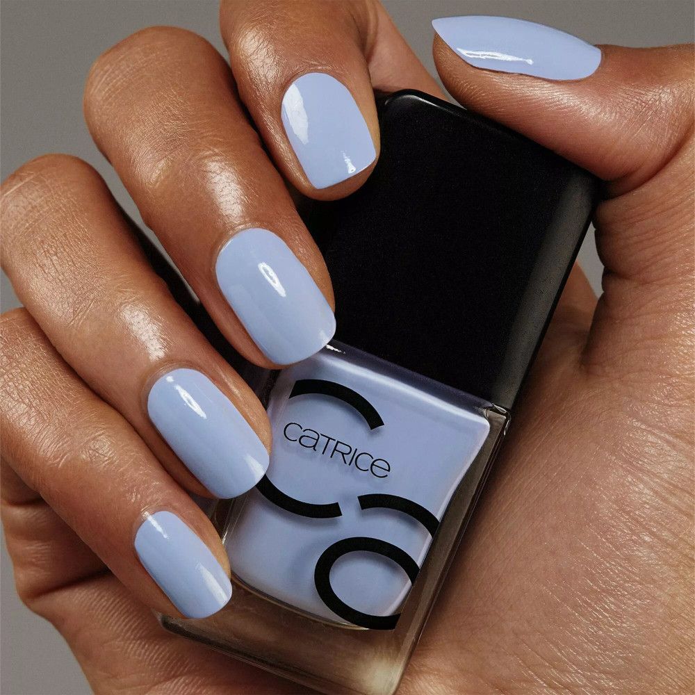 Main avec ongles vernis et flacon de vernis à ongles. Catrice est écrit sur le flacon.