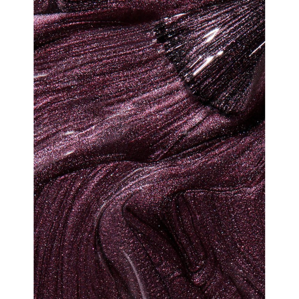 Pinceau de vernis à ongles sur vernis à ongles foncé brillant. Le vernis a un effet scintillant.