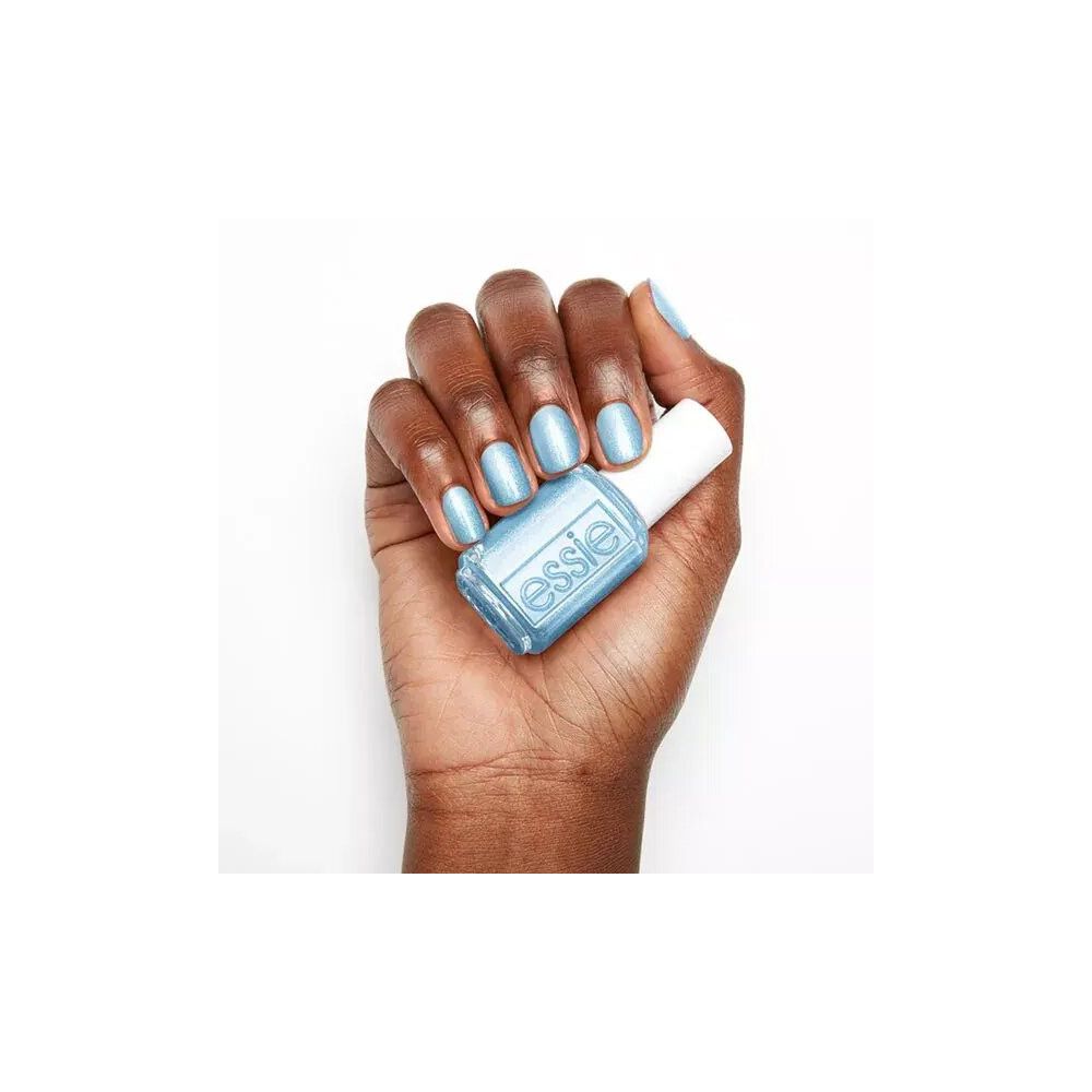 Hand houdt een flesje Essie nagellak vast. Lichtblauwe lak, witte dop, Essie-logo.