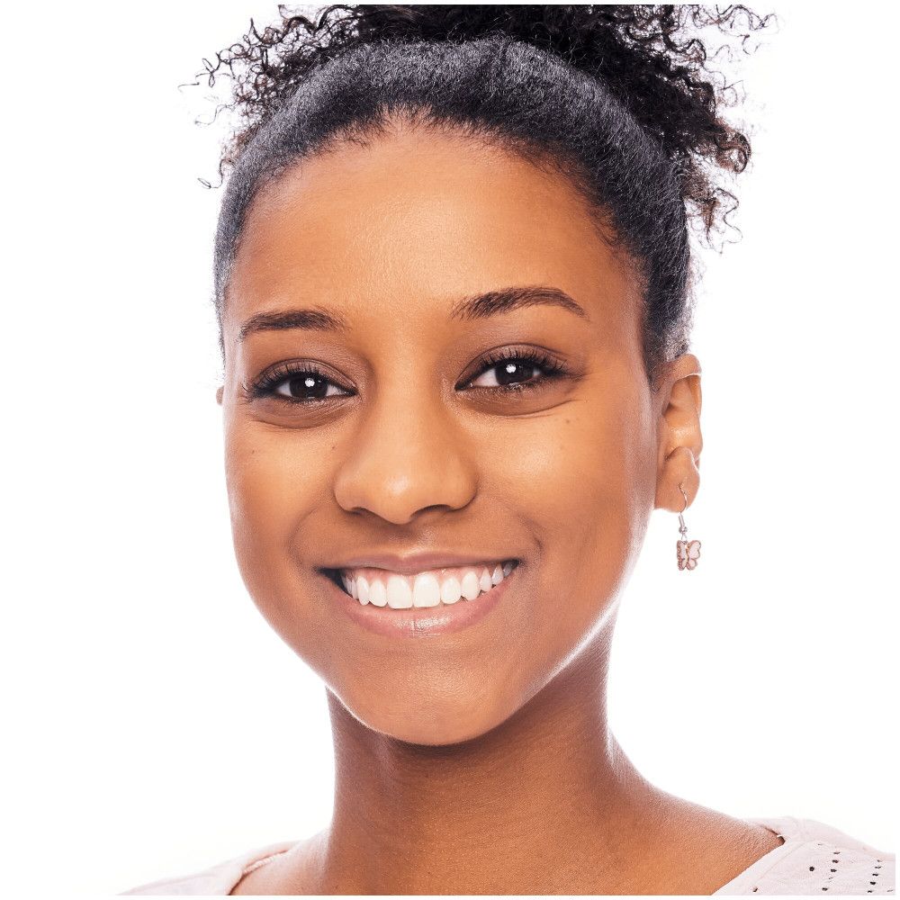 Portret van een lachende vrouw met een donkere huid. Ze draagt oorbellen en heeft haar haar opgestoken.