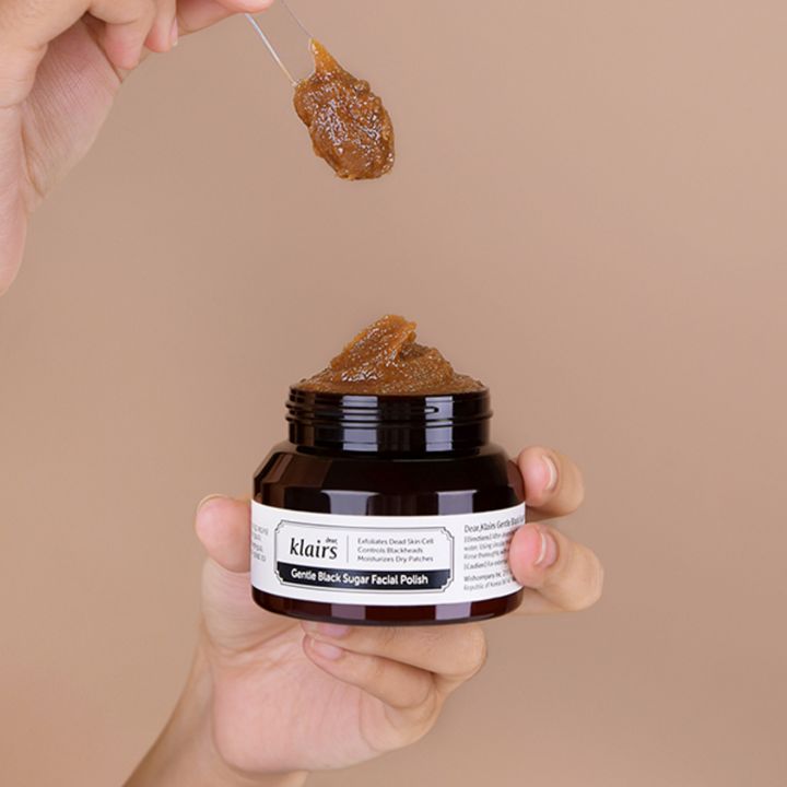 Potje bruine crème in handen. Lepel met crème erboven. Opschrift: Klairs.