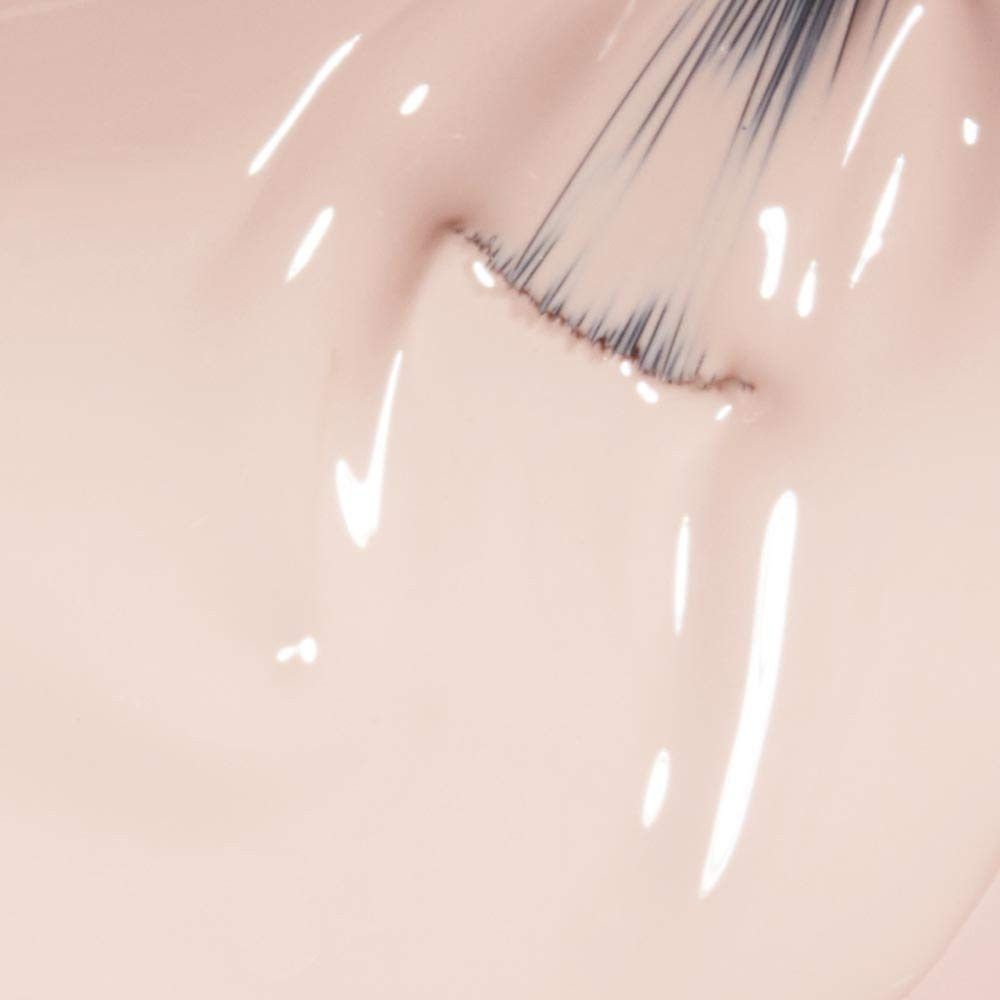 Nagellak-applicator in lichte tint. Penseel raakt het oppervlak aan. Glanzende textuur met reflecties.