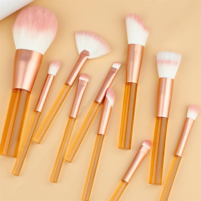 Ensemble de pinceaux de maquillage avec manches orange transparents et poils roses. Différentes formes et tailles.
