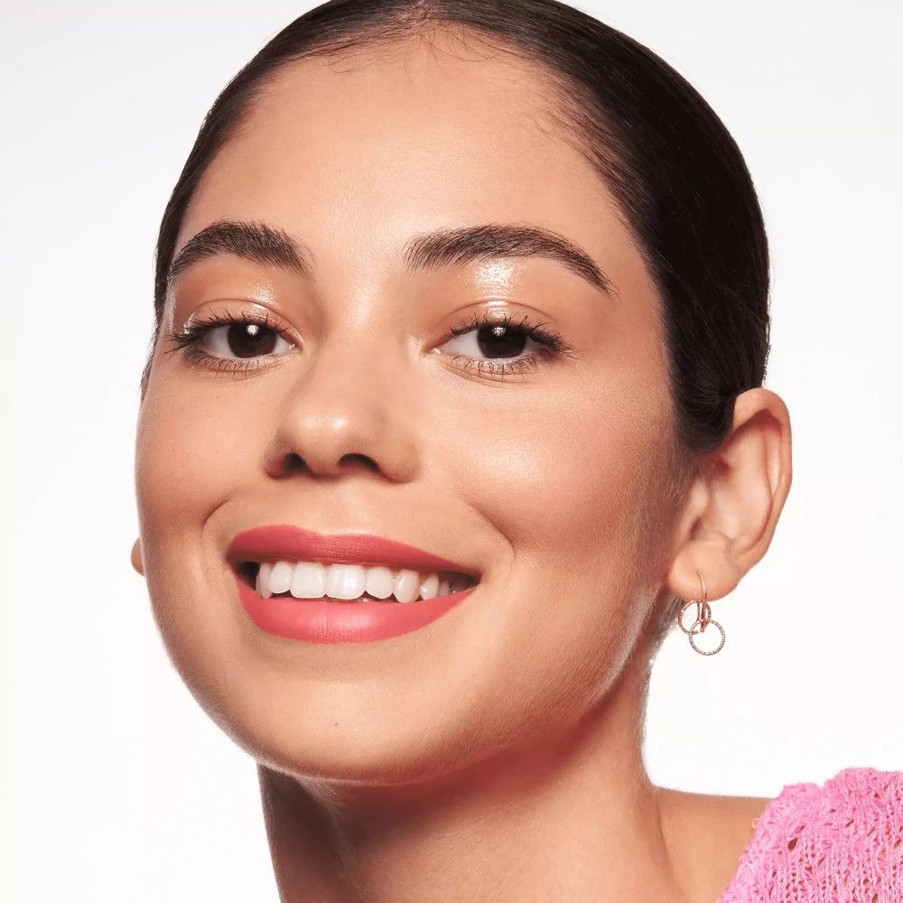 Vrouw met roze lippenstift. Draagt oorbellen.