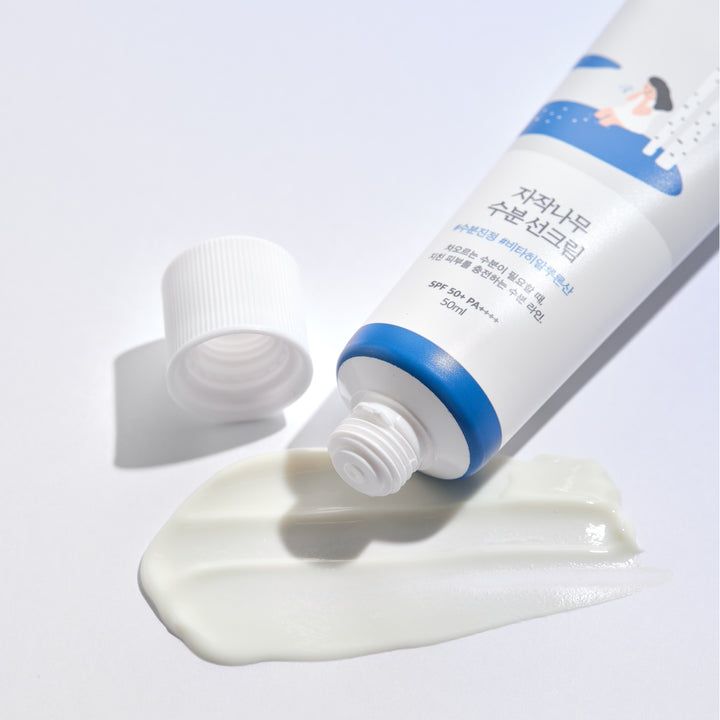 Tube blanc avec bouchon bleu, produit pressé. Crème blanche sur fond blanc. Bouchon à côté.