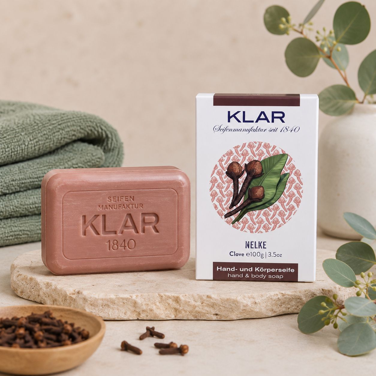 Savon mains et corps Klar Seifen Nelke sur pierre, près de l'emballage et serviette.