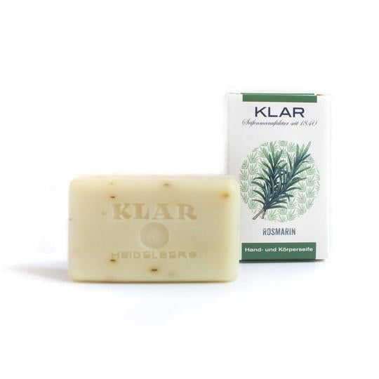 Savon rectangulaire avec gaufrage : KLAR. À côté, emballage avec branche de romarin et inscription : KLAR, Rosmarin, savon mains et corps.