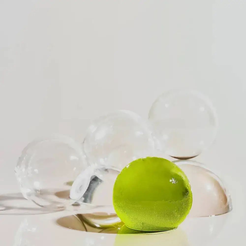 Groenachtige bal op transparante halve bollen. Meerdere transparante bollen. Lichte omgeving.