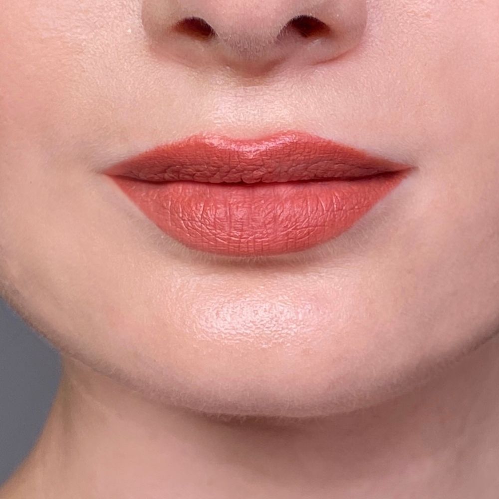 Close-up van lippen met koraalrode lippenstift. Lichte huidskleur. Boven- en onderlip zichtbaar.
