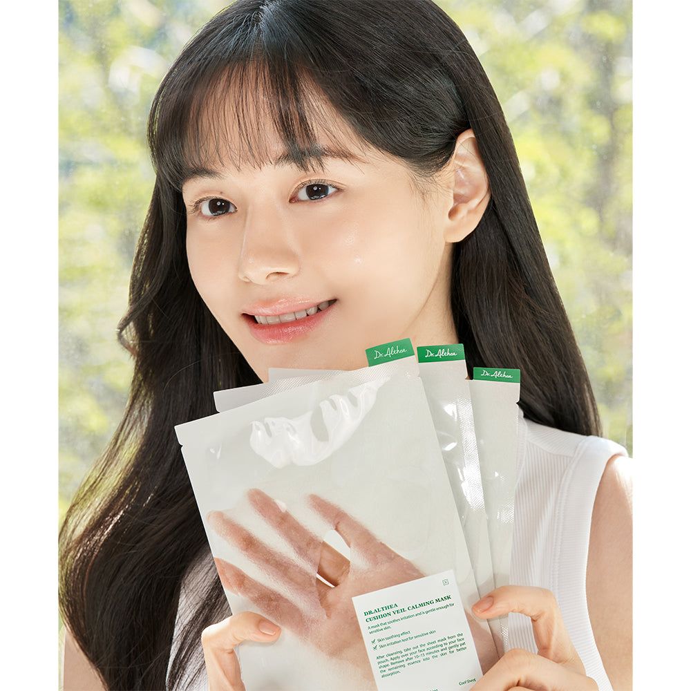 Een vrouw houdt meerdere Dr. Althea Cushion Veil kalmerende maskers voor zich.