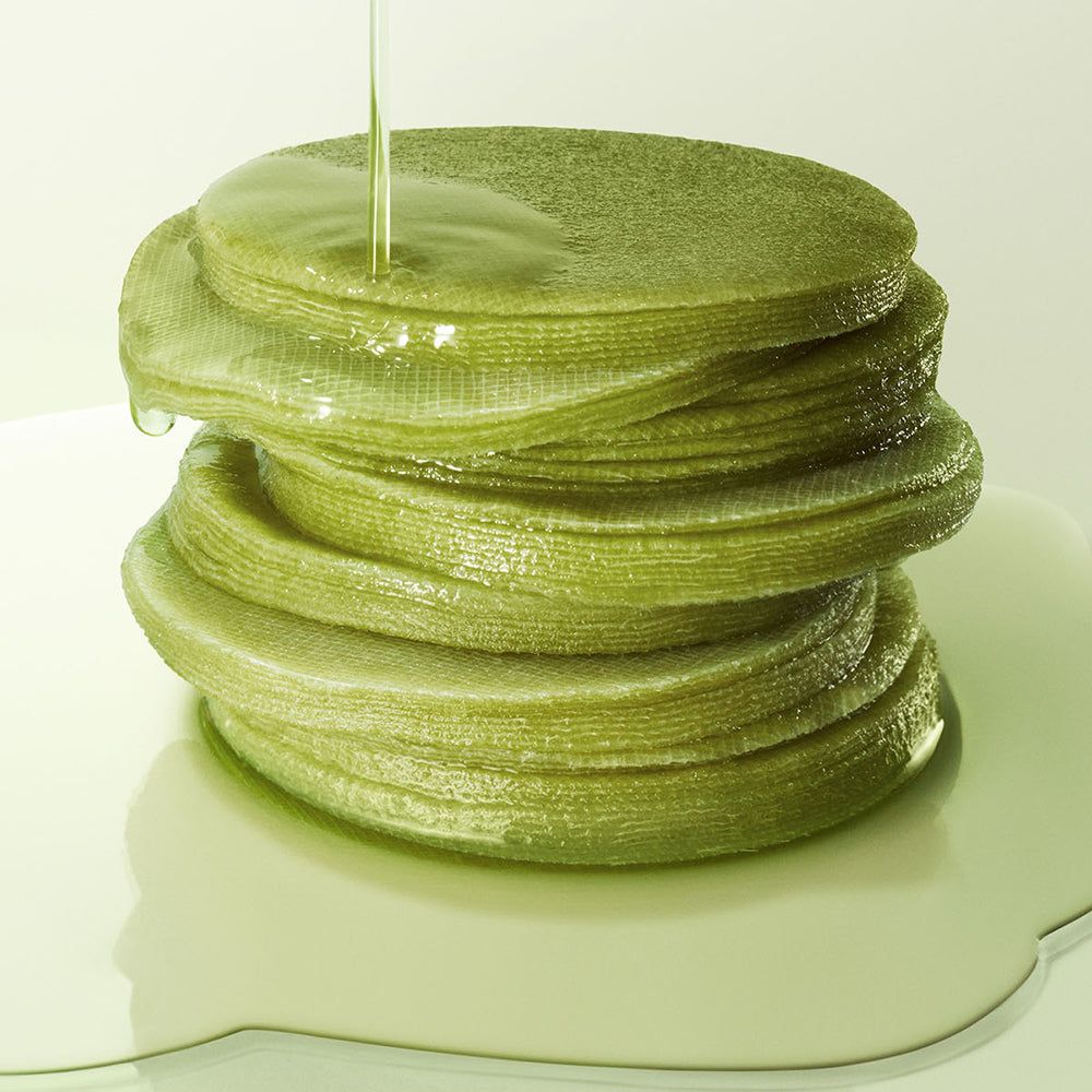 Pads de thé matcha verts empilés, arrosés de liquide.