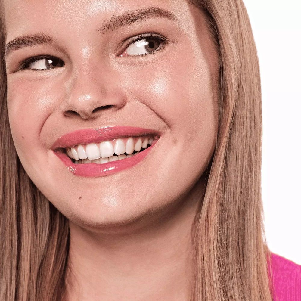 Portret van een lachende vrouw. Ze draagt roze lipgloss. Lang blond haar. Close-up.