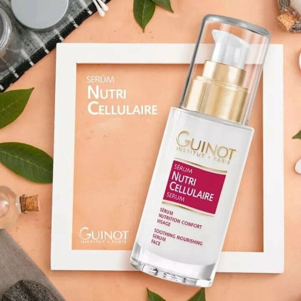 Guinot Serum Nutri Cellulaire. Fles op decoratieve achtergrond. Witte fles met pomp, rood etiket, gouden ring.