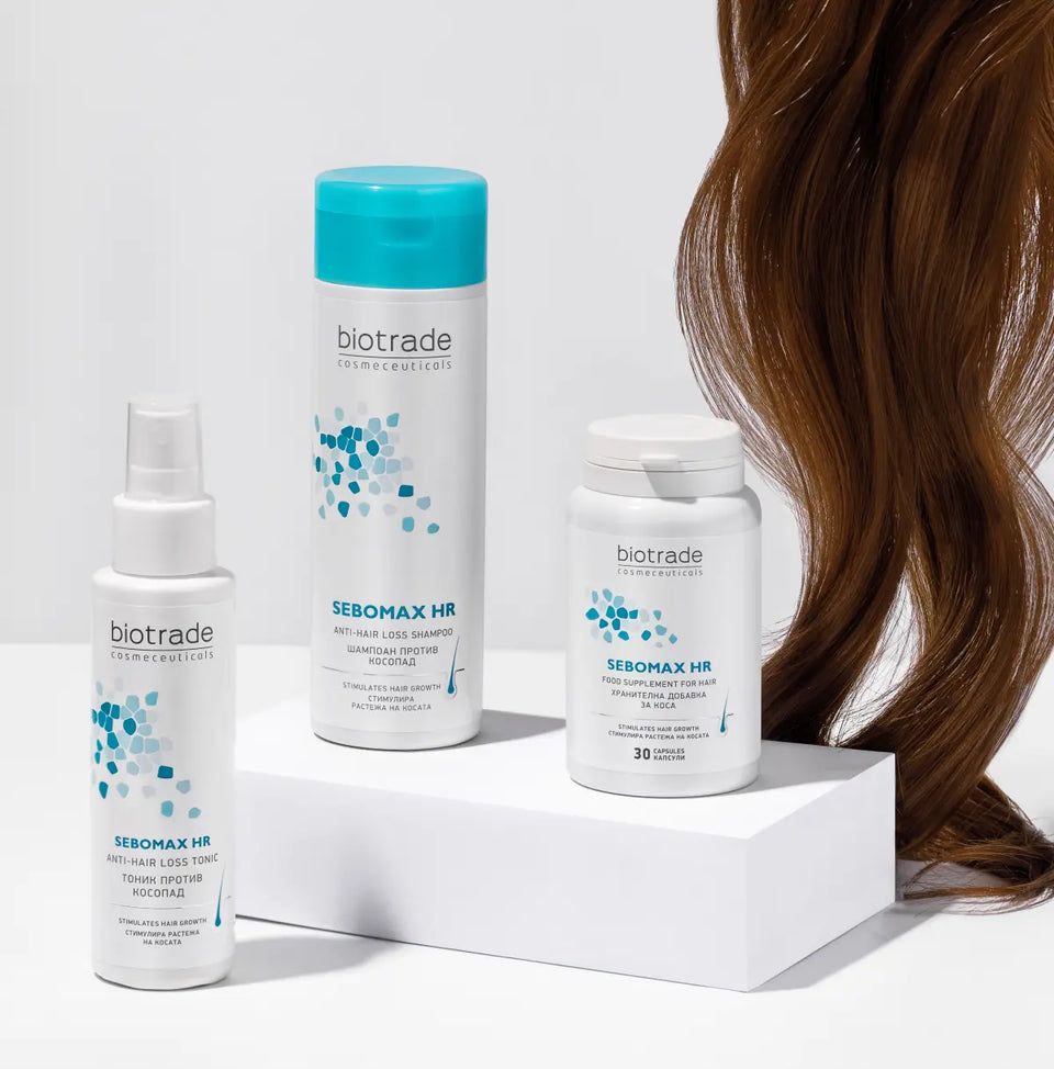 Trois produits Biotrade: shampooing, spray et comprimés. Texte: Sebomax HR. Flacons et boîte blancs. Cheveux bruns en arrière-plan.