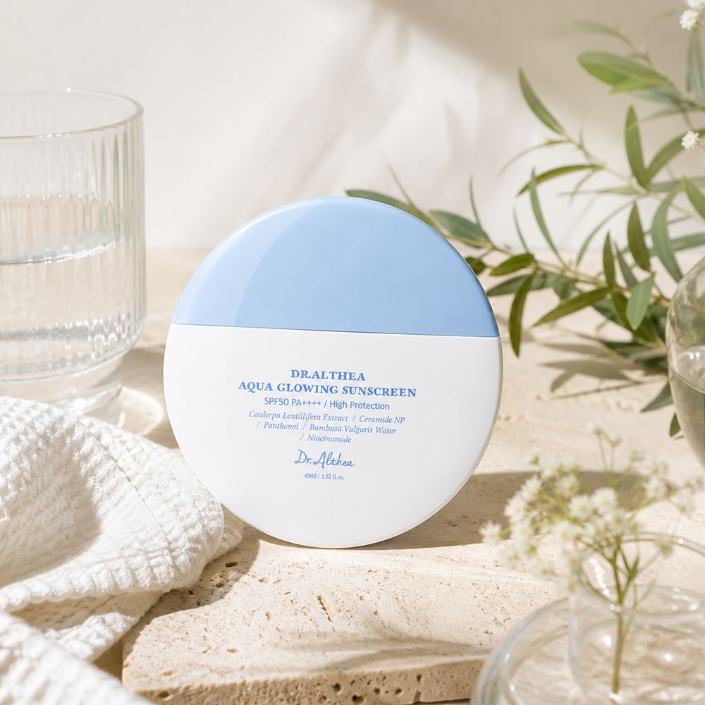 Crème solaire Dr. Althea Aqua Glowing dans un contenant blanc et bleu, avec texte.