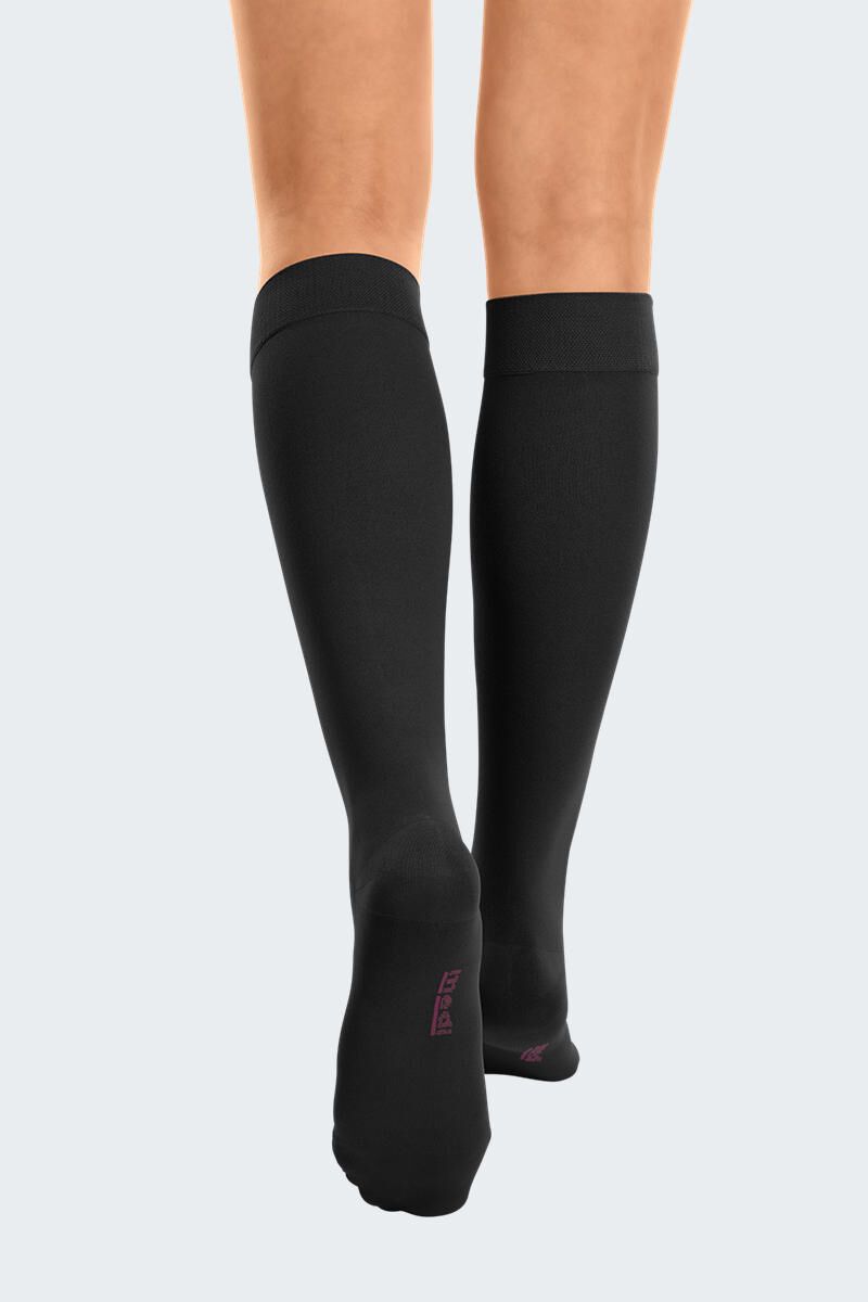 Bas de compression noirs sur les jambes. Bord en tricot. Vue arrière.