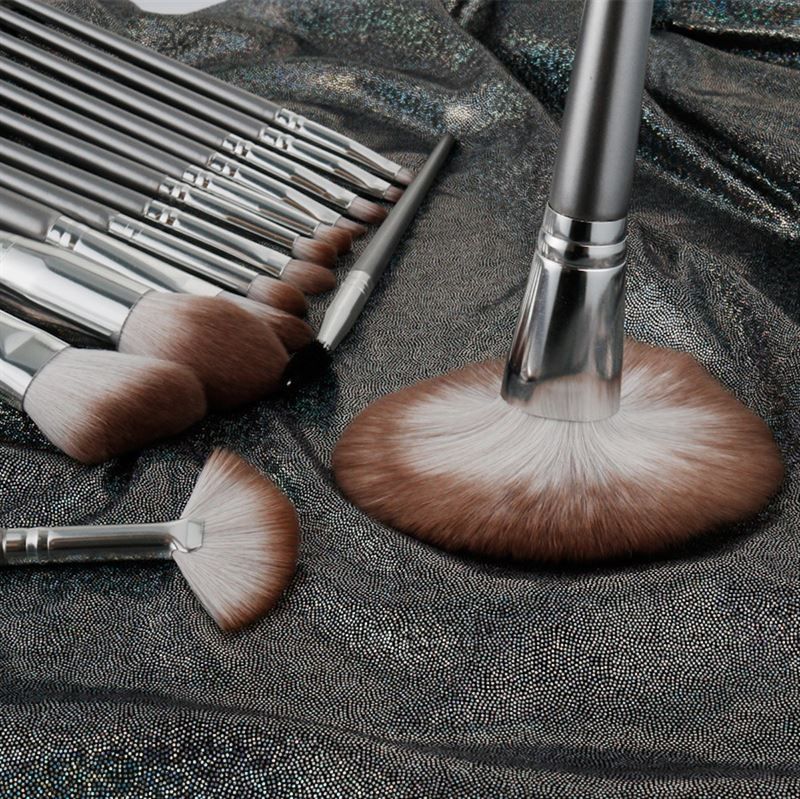 Close-up van een make-up borstelset op glanzende, zilverkleurige stof. Verschillende borstelvormen.