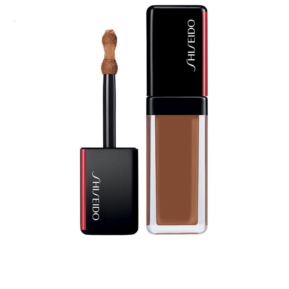 Flacon de correcteur beige avec bouchon noir. Applicateur visible. Logo Shiseido sur le bouchon.