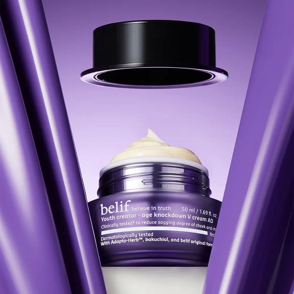 Open paarse pot met crème. Zwarte deksel erboven. Opschrift: belif, Youth creator - age knockdown V cream AD. Tekst: Klinisch getest.