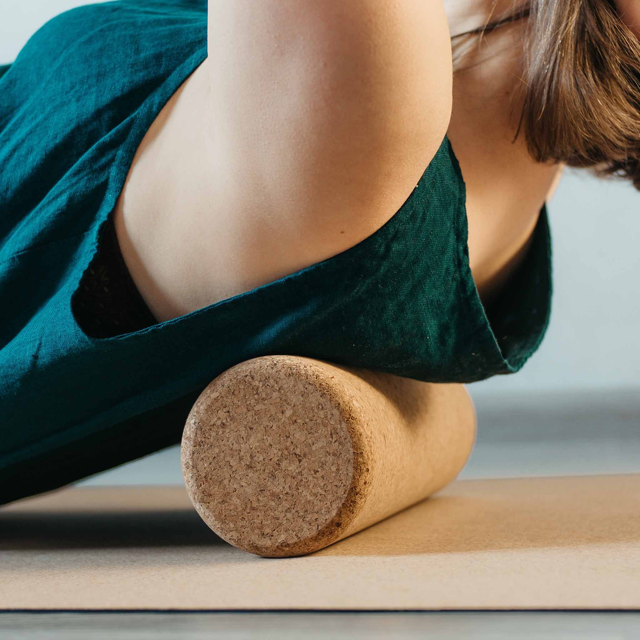 Personne utilisant un rouleau de fascia en liège. Rouleau marron sous le dos sur un tapis.