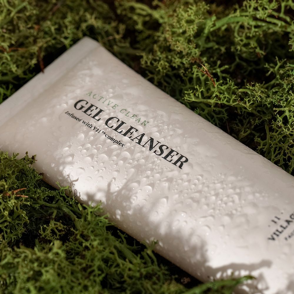 Witte tube met opschrift ACTIVE CLEAN GEL CLEANSER, bedekt met waterdruppels, op mos.