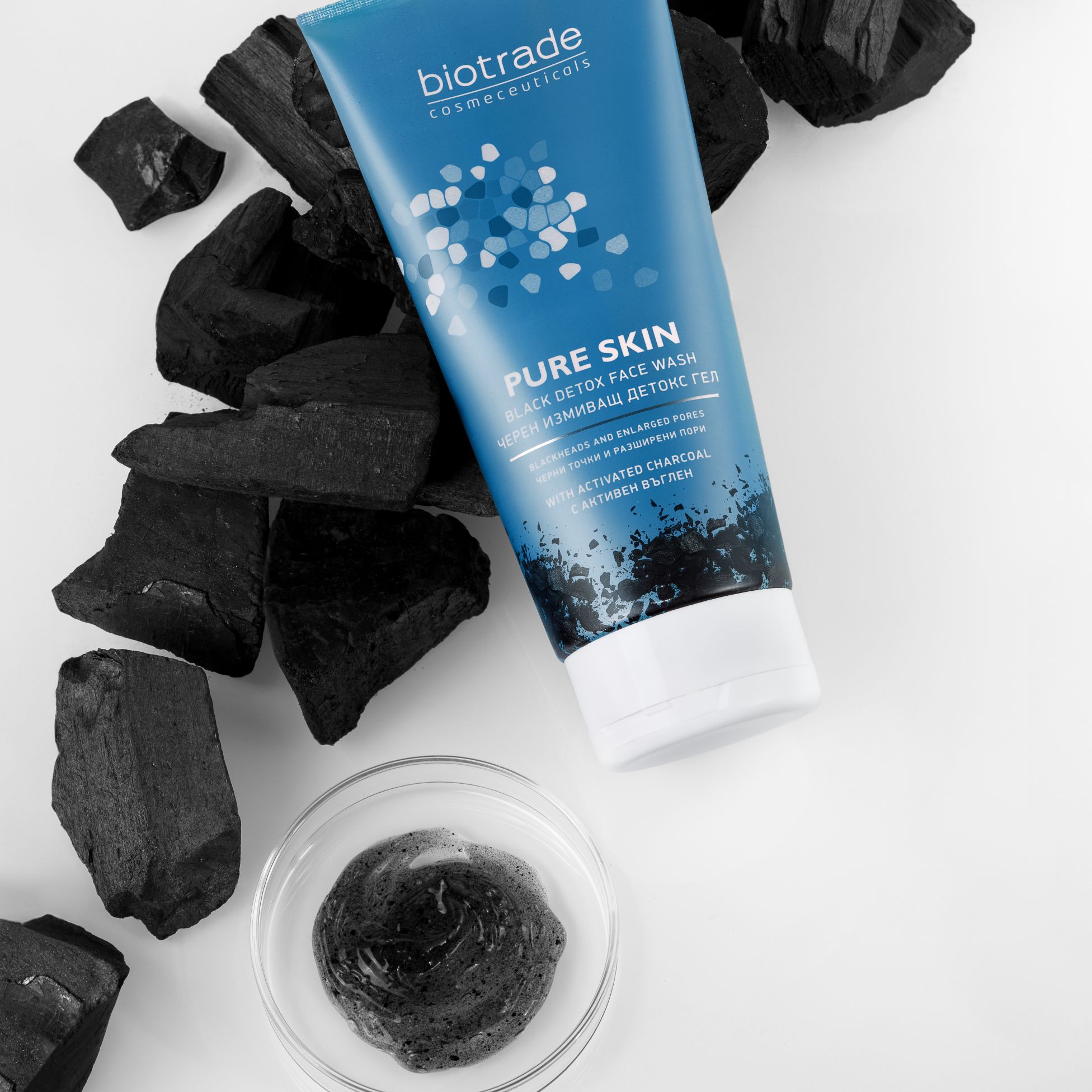 Blauwe tube met witte dop en houtskool. Schaal met zwarte gel. Opschrift: Biotrade, Pure Skin Black Detox Face Wash.