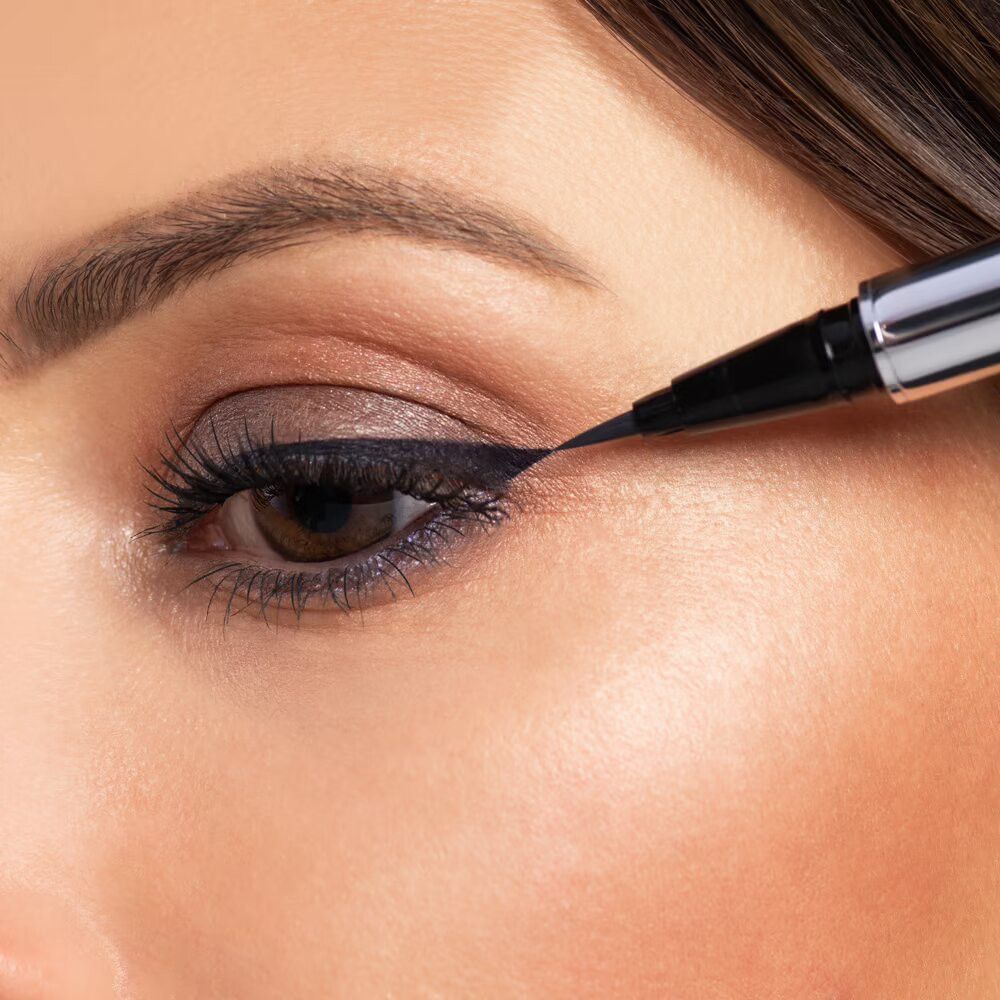 Close-up van een oog dat wordt opgemaakt met een zwarte eyeliner. De eyeliner is zichtbaar.
