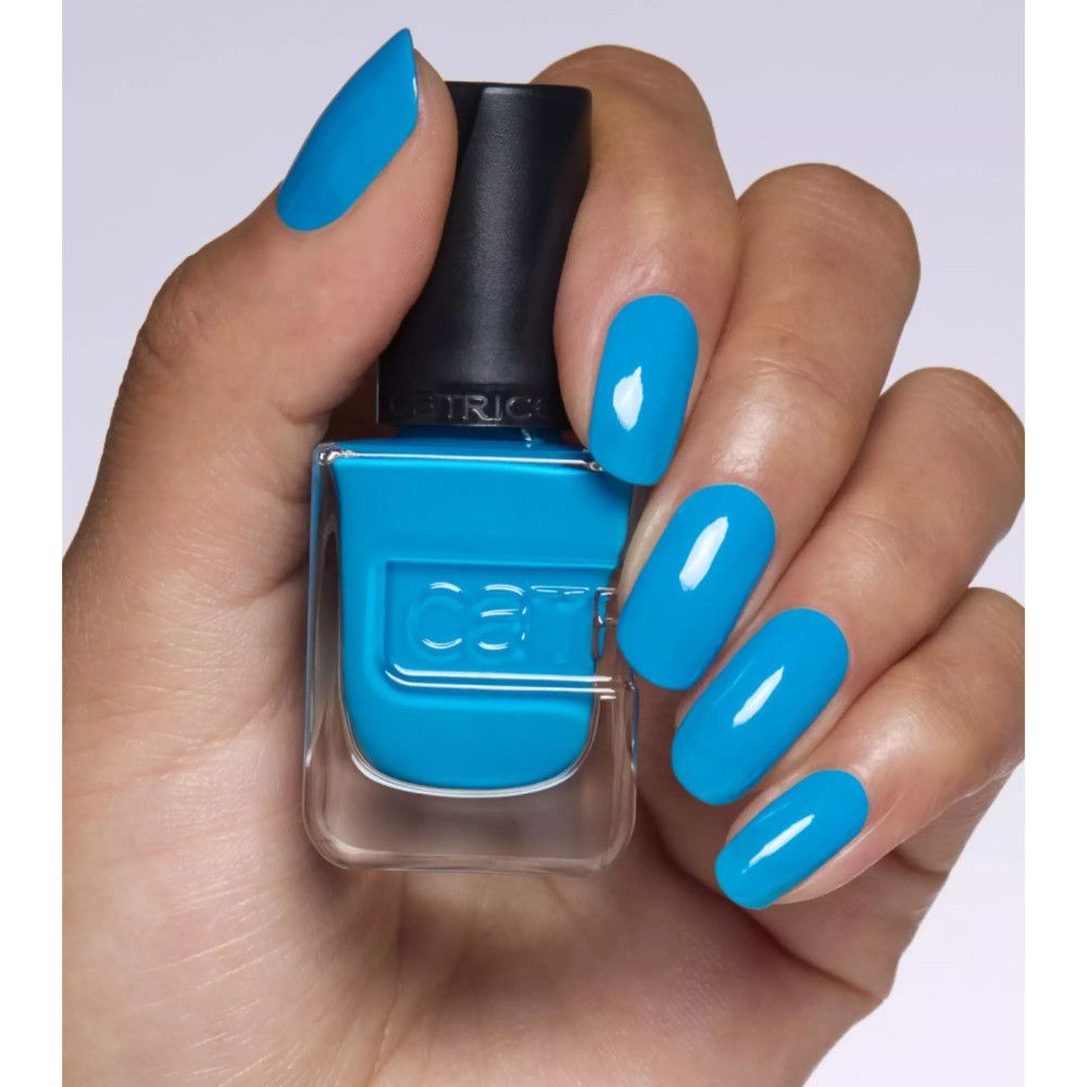 Main avec ongles vernis et flacon de vernis à ongles. Les ongles et le vernis sont bleus. "Catrice" est écrit sur le flacon.