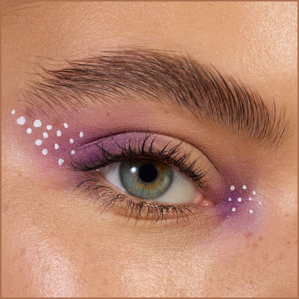 Gros plan sur un œil avec fard à paupières violet et points blancs.