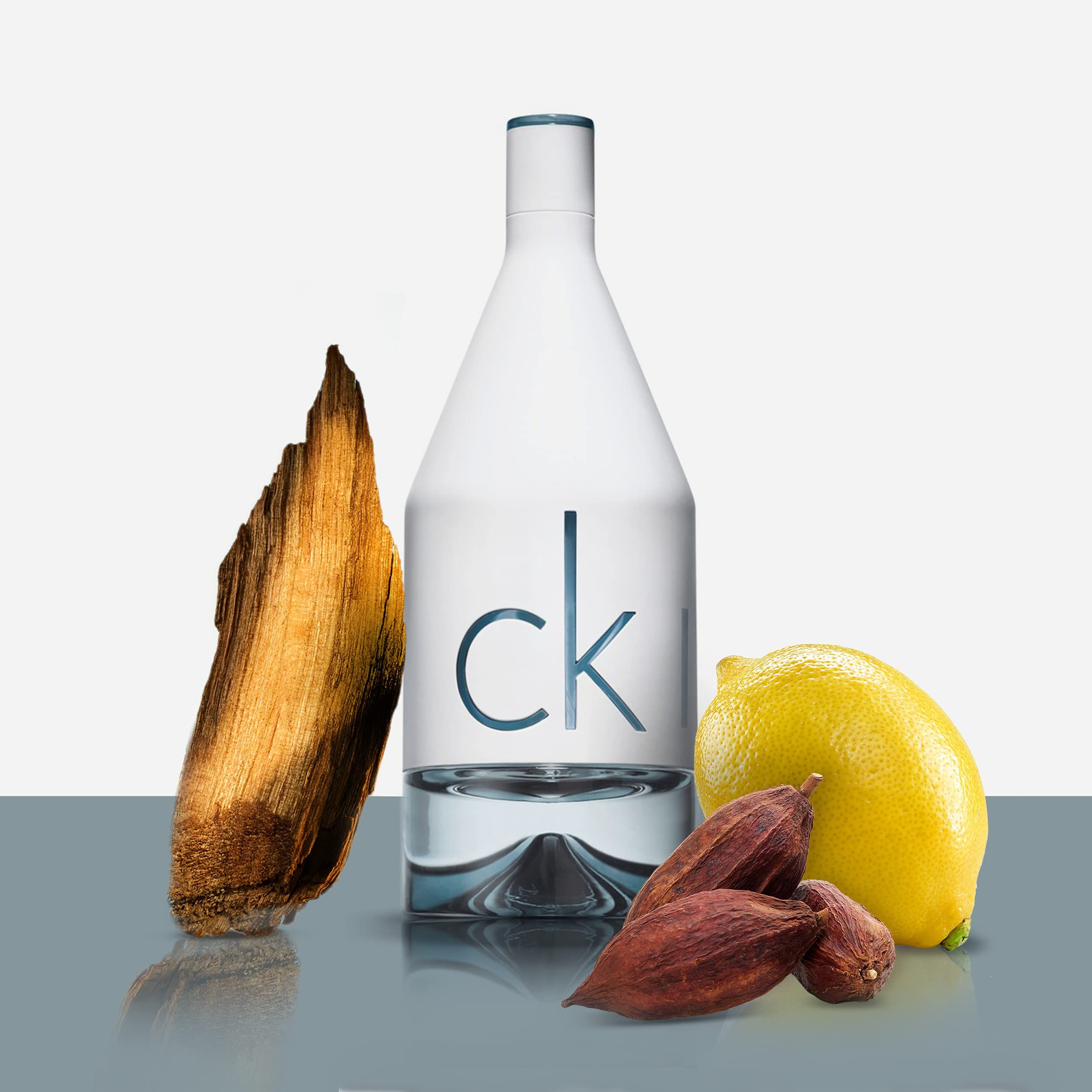 Witte fles met "ck" en ingrediënten: hout, citroen en cacaobonen.