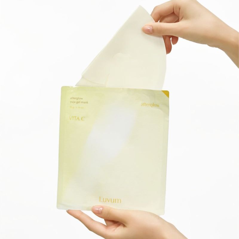 Mains tenant un masque en gel hors de l'emballage. Emballage avec texte 'Luvum' et 'Vita C'.
