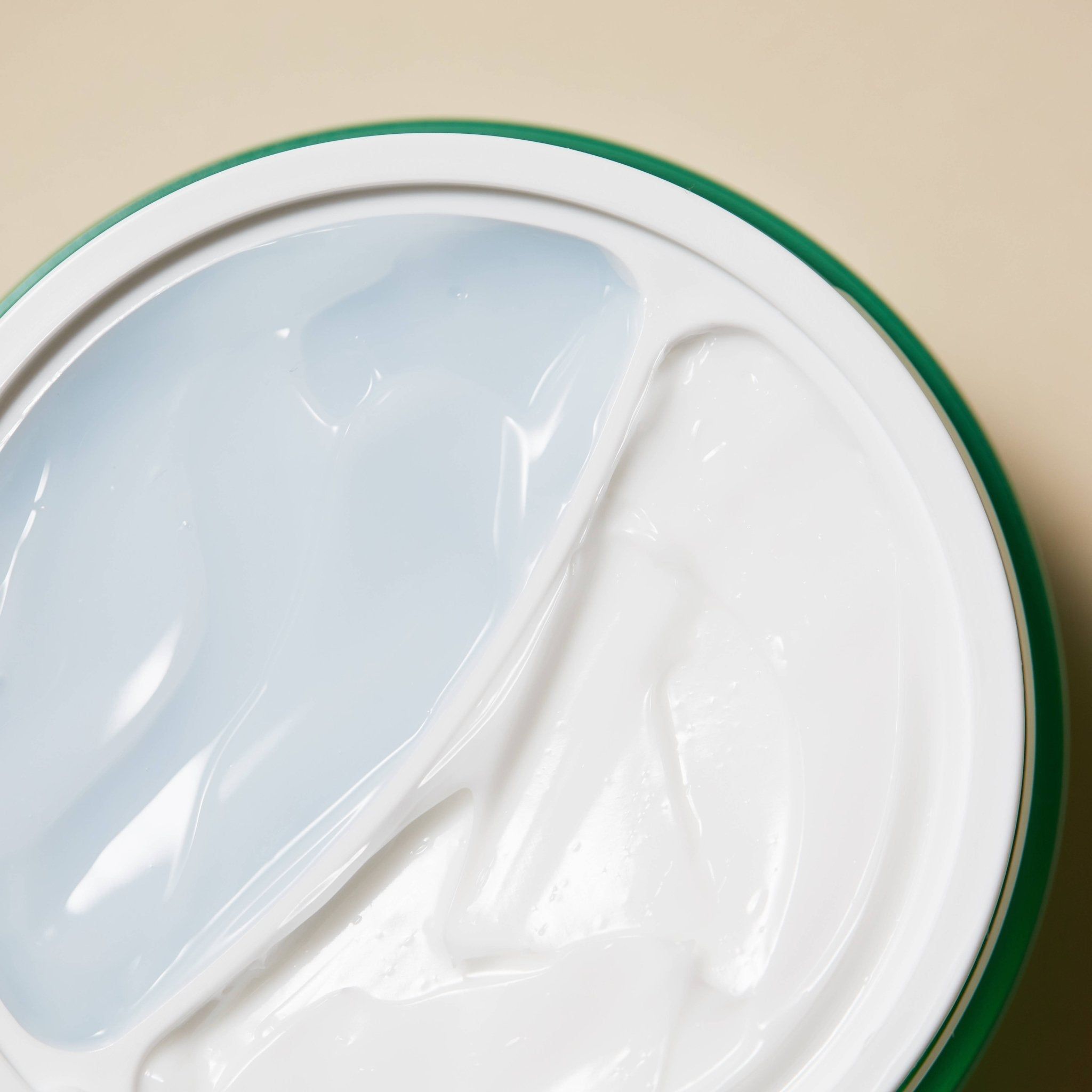 Crème pot met twee crèmes. Eén crème is wit, de andere blauw. Groene pot.