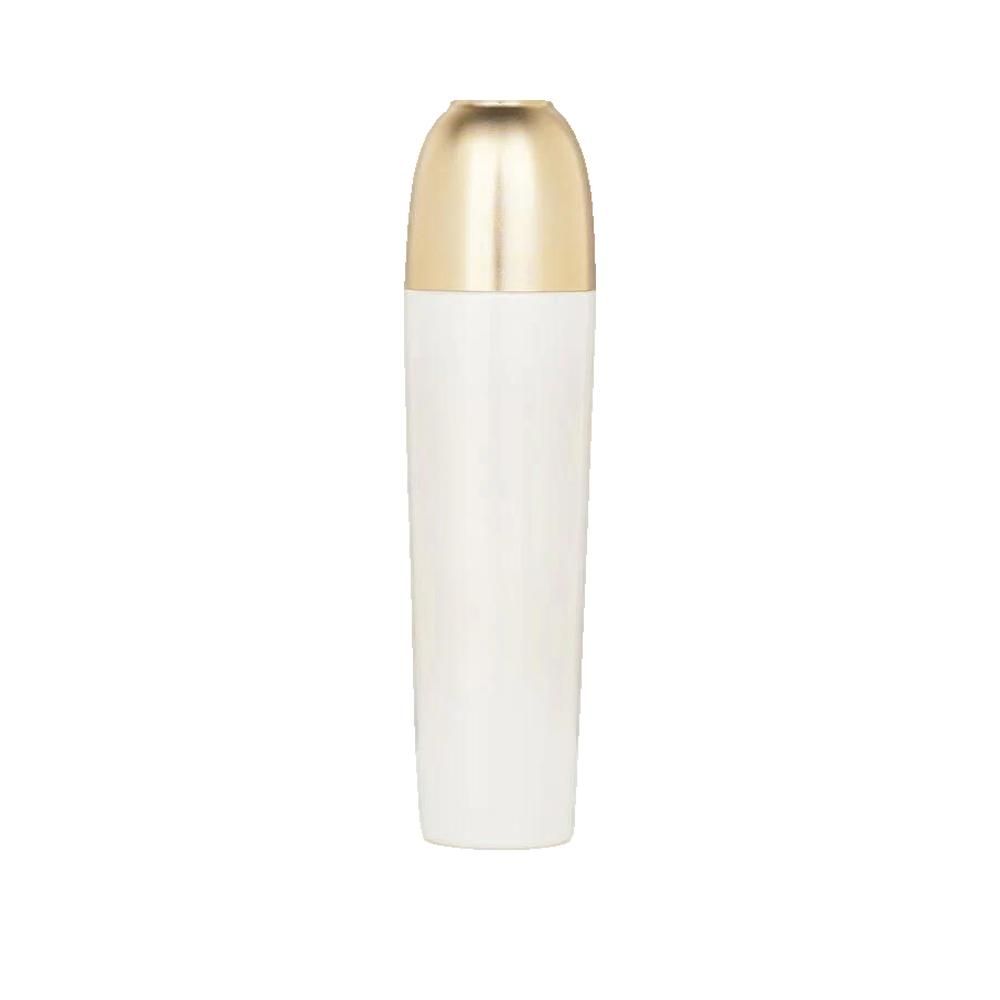 Flacon cylindrique blanc avec bouchon doré. Le bouchon est allongé et arrondi. Aucun autre détail visible.