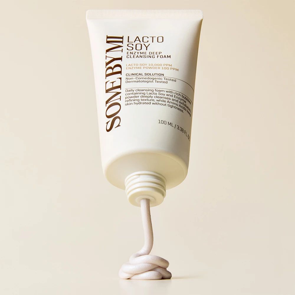 Un tube de mousse nettoyante blanche, d'où sort un filet de produit.
