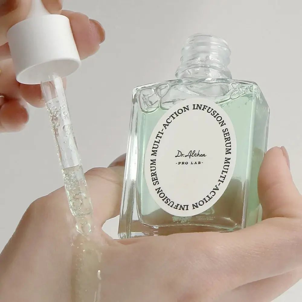 Main tenant un flacon de sérum et une pipette. Le sérum est versé sur la main. Flacon avec étiquette.