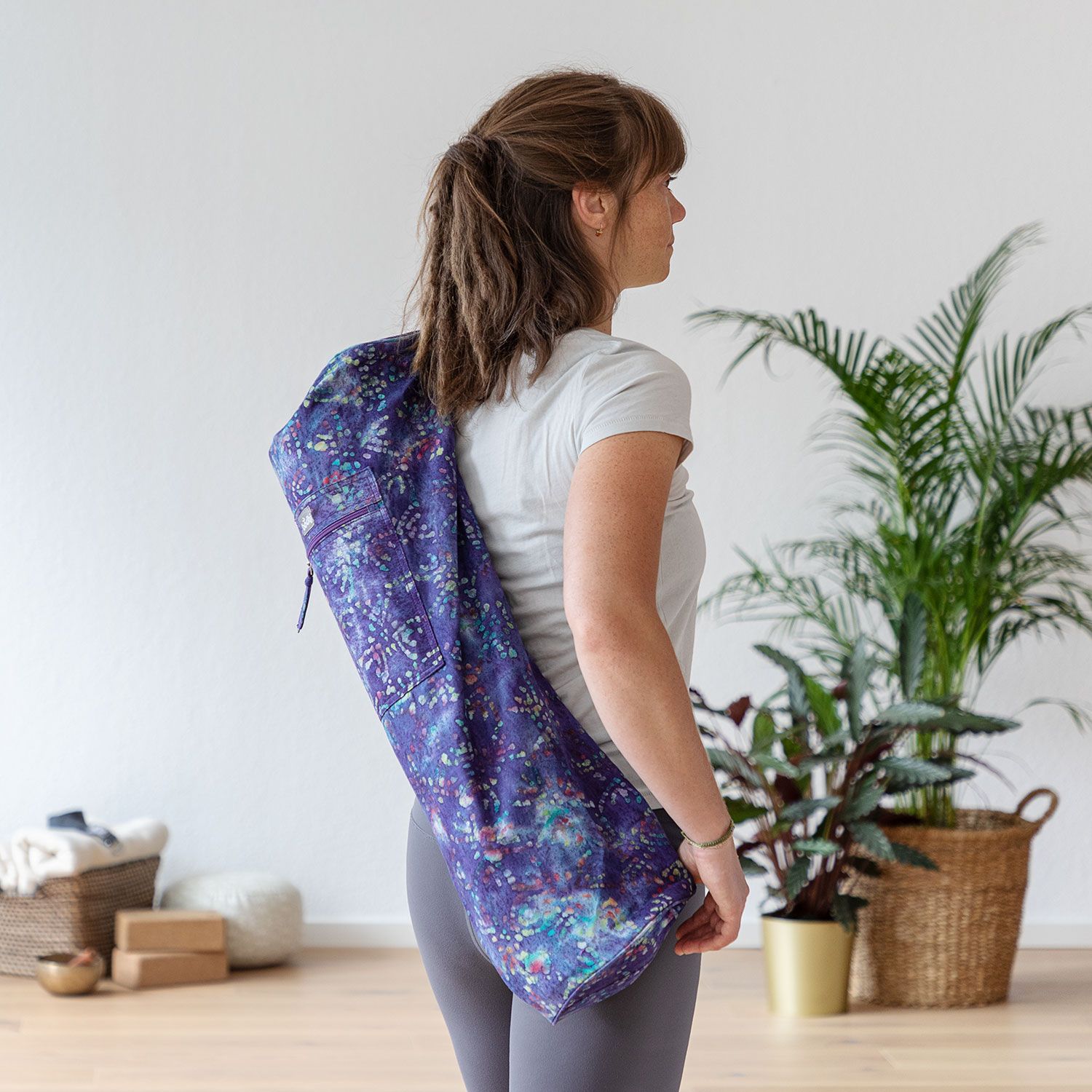 Vrouw draagt yogatas, paars met patroon, over schouder. Binnenkant zichtbaar. Lichte omgeving.
