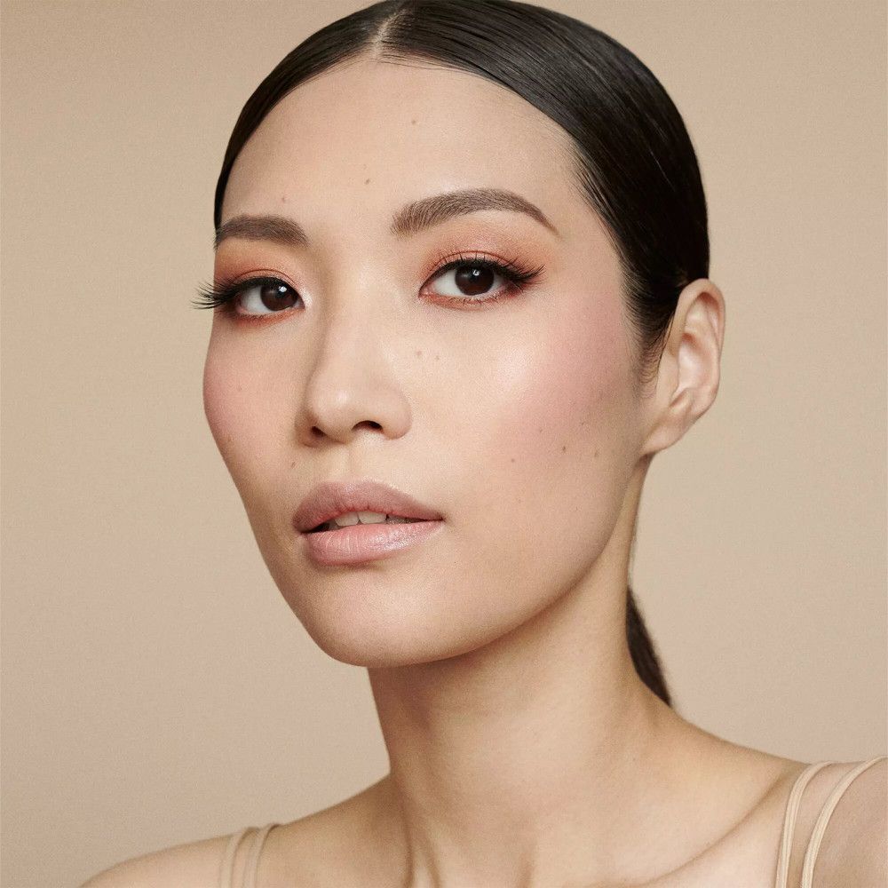 Portrait d'une femme maquillée. Sourcils dessinés, fard à paupières, blush et rouge à lèvres.