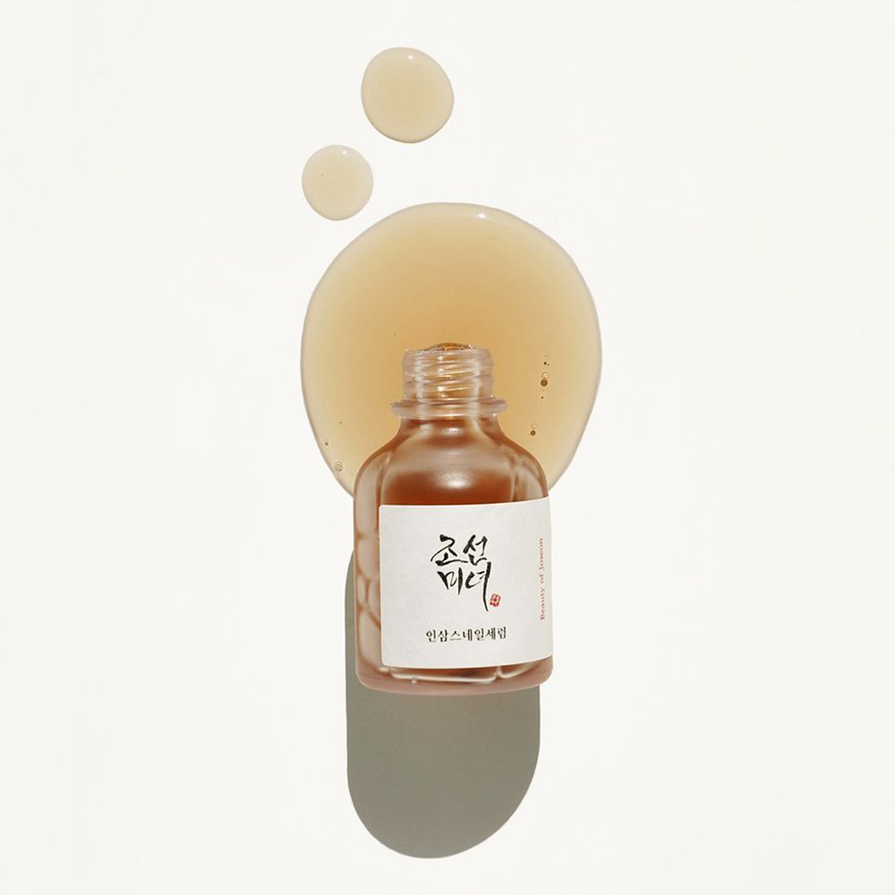 Transparante fles met serum en druppels. Etiket met Koreaanse tekst. Op lichte achtergrond.