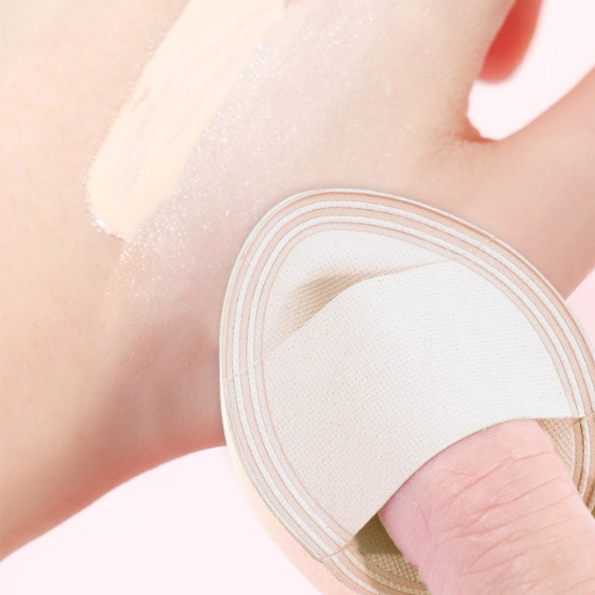 Éponge de maquillage beige avec un doigt à l'intérieur, appliquée sur une paume.