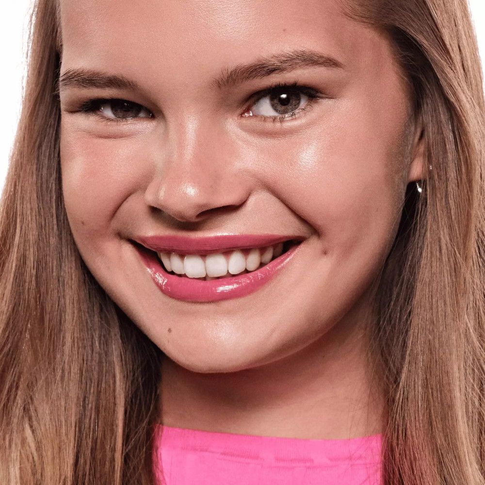 Portrait d'une femme avec un LIP TINT rose. Elle sourit.