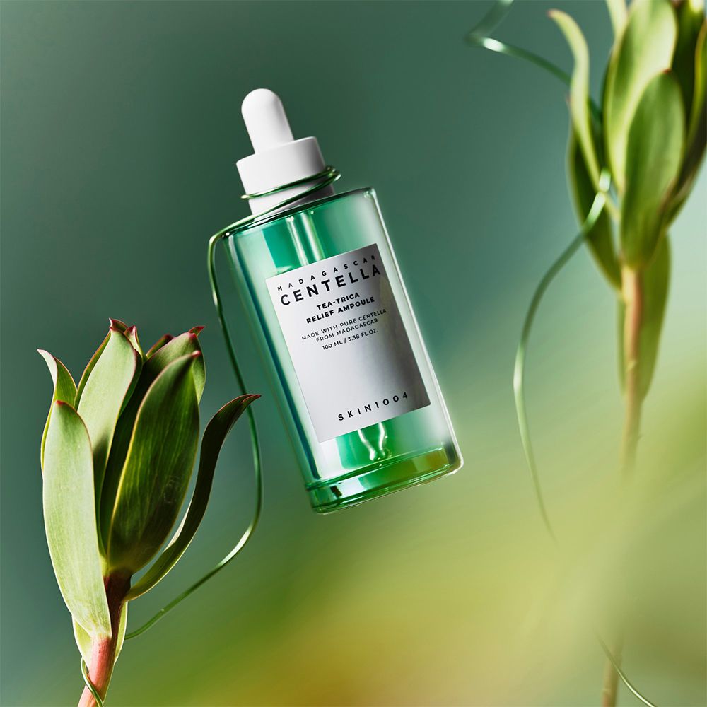 Flacon en verre vert avec pipette, entouré de plantes vertes et de fil. En suspension dans l'air.