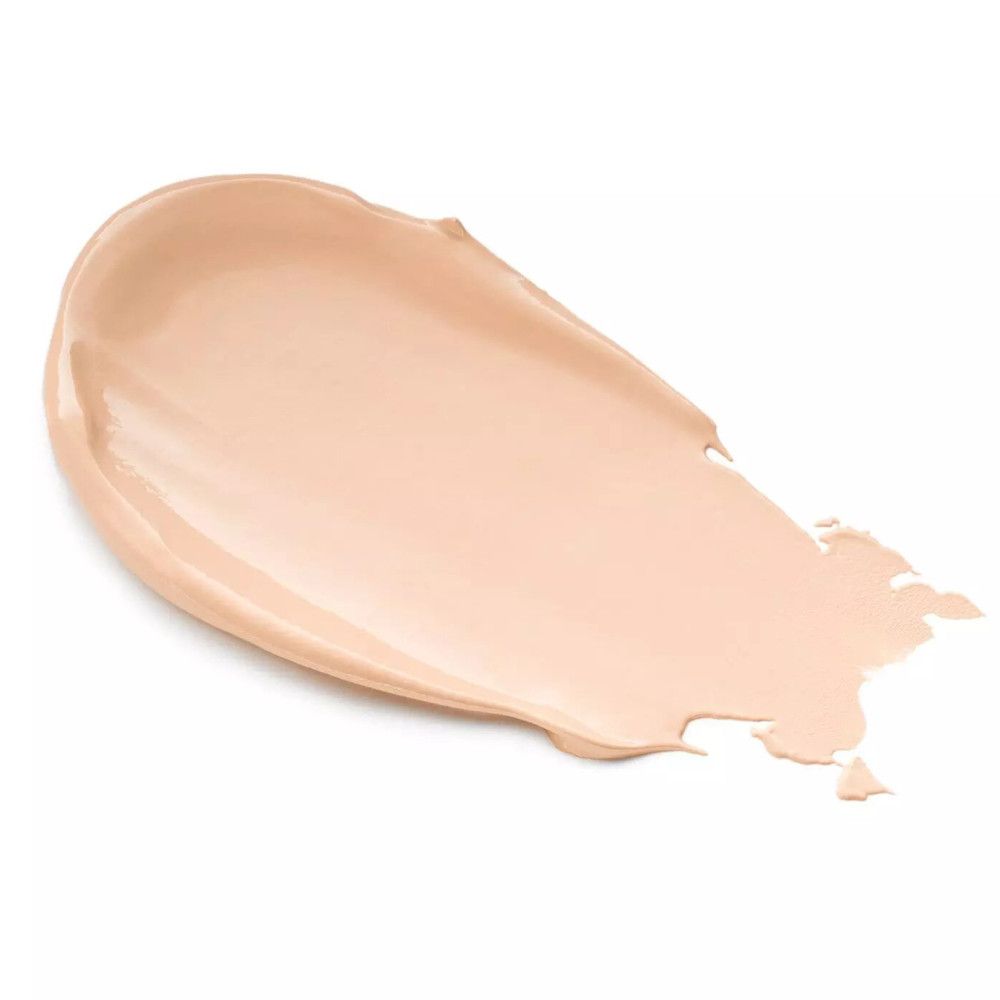Un trait de crème correctrice couleur crème sur fond blanc. La texture est lisse et légèrement brillante.