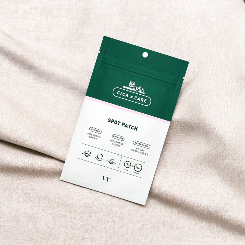 Emballage vert avec texte blanc: Cica x Care, Spot Patch. Logo: Tigre. Posé sur tissu clair.