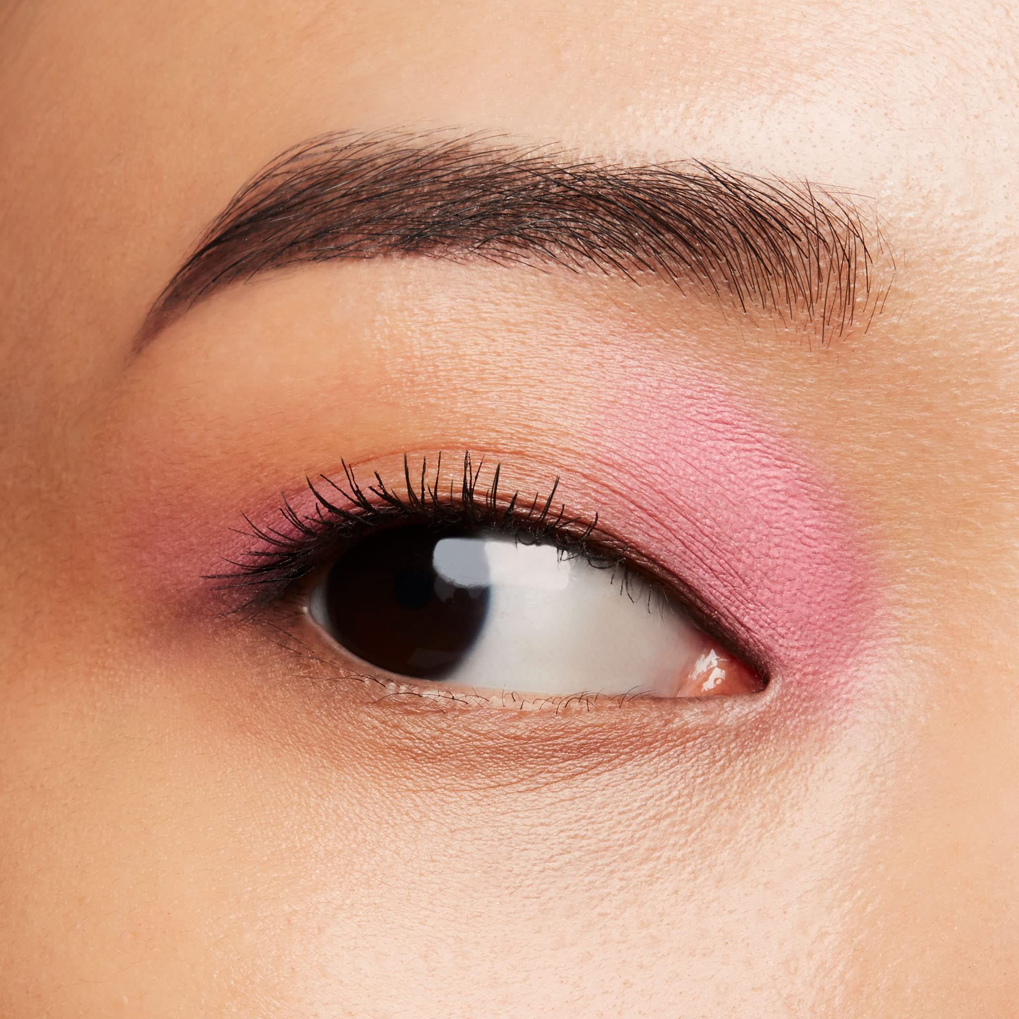Œil avec fard à paupières rose. Sourcil brun, cils. Regard sur le côté.