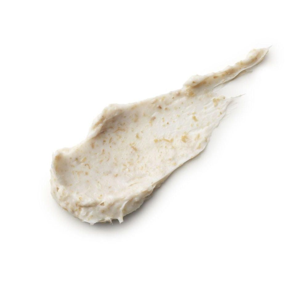 Crème étalée avec particules visibles. Couleur claire, sur fond blanc.